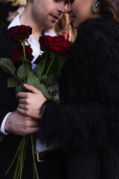 Vista cortada do homem segurando rosas vermelhas perto da mulher — Fotografia de Stock