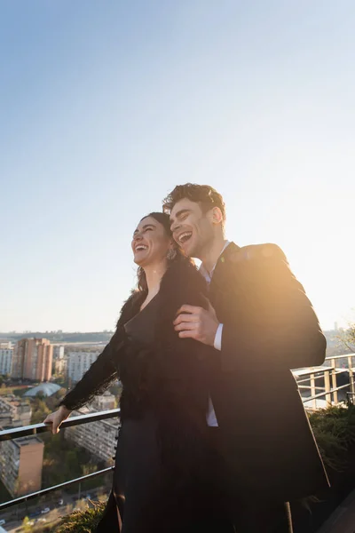 Man and woman laughing while standing on roof — Stock Photo