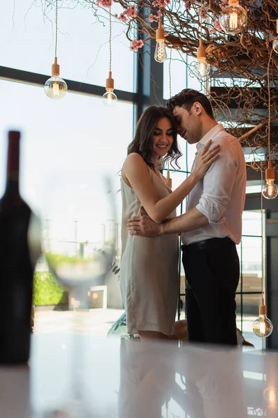 Man in shirt hugging happy woman in slip dress in restaurant — Stock Photo