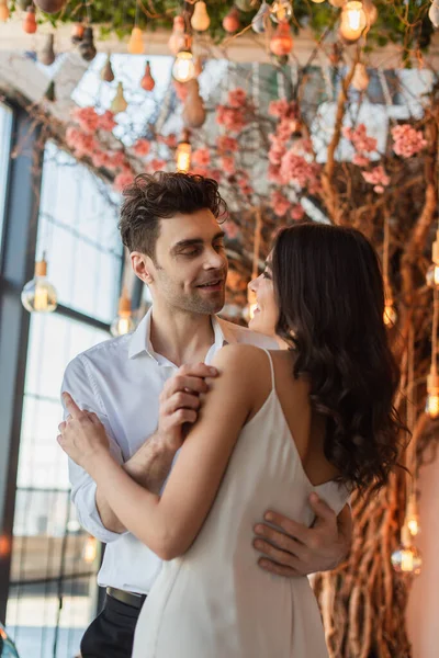 Glücklicher Mann umarmt junge brünette Frau in Restaurant — Stockfoto