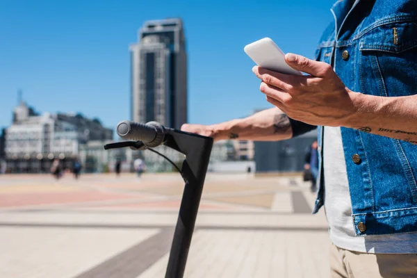 Partial view of man holding smartphone outside - foto de stock