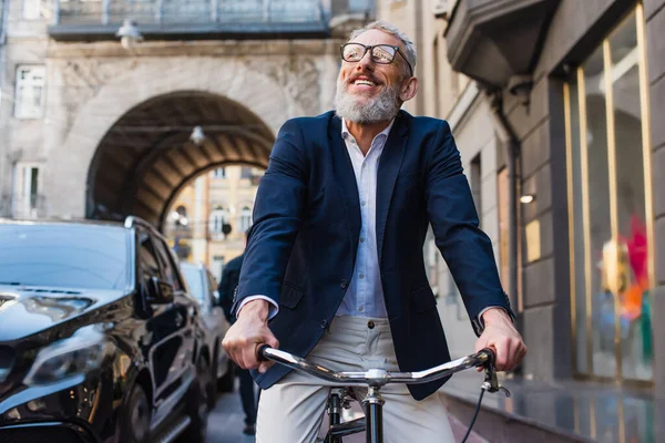 Fröhlicher bärtiger Mann mit Brille radelt auf urbaner Straße — Stockfoto