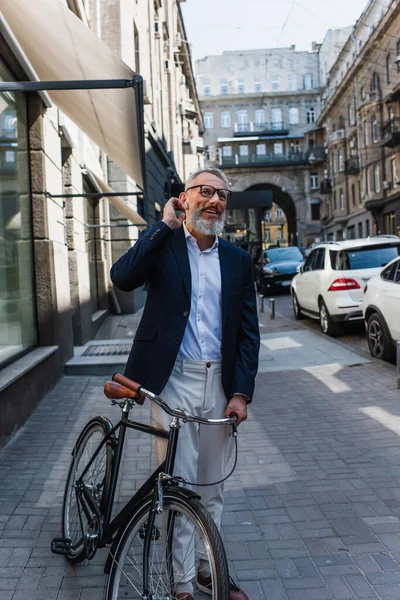 Glücklicher älterer Mann hört Musik in Kopfhörern in der Nähe von Fahrrad — Stockfoto