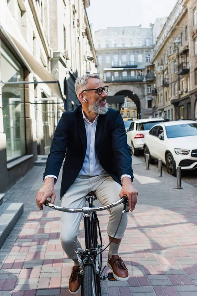 Lächelnder älterer Mann, der Musik in Kopfhörern hört und Fahrrad fährt — Stockfoto