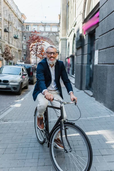 Улыбающийся мужчина слушает музыку в наушниках и ездит на велосипеде — стоковое фото