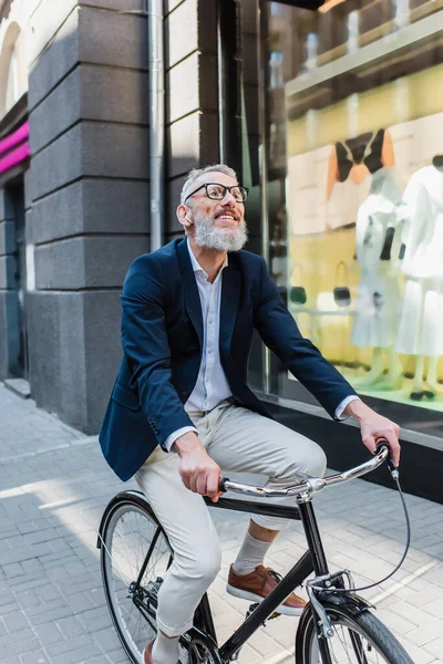 Glücklicher Mann mittleren Alters, der Musik in Kopfhörern hört und Fahrrad fährt — Stockfoto