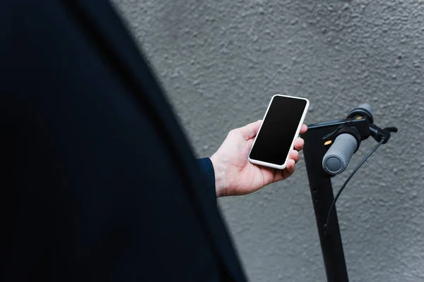 Teilbild eines reifen Mannes mit Smartphone mit leerem Bildschirm in der Nähe von E-Scooter — Stockfoto