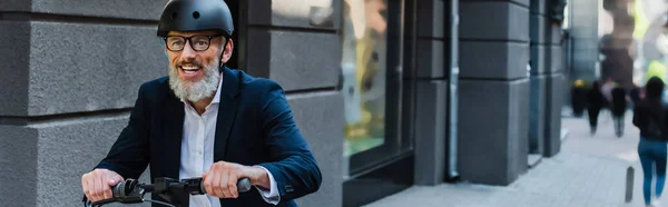 Joyful mature businessman in blazer and helmet riding e-scooter, banner — Foto stock