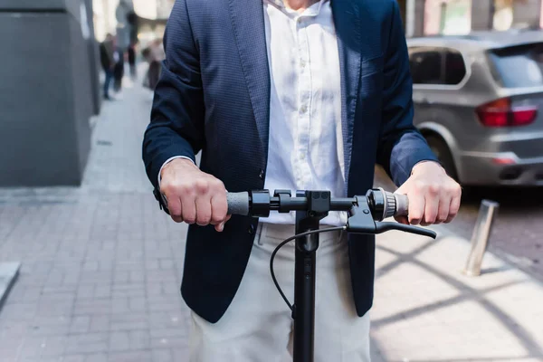 Cropped view of mature businessman in blazer riding electric scooter — Fotografia de Stock