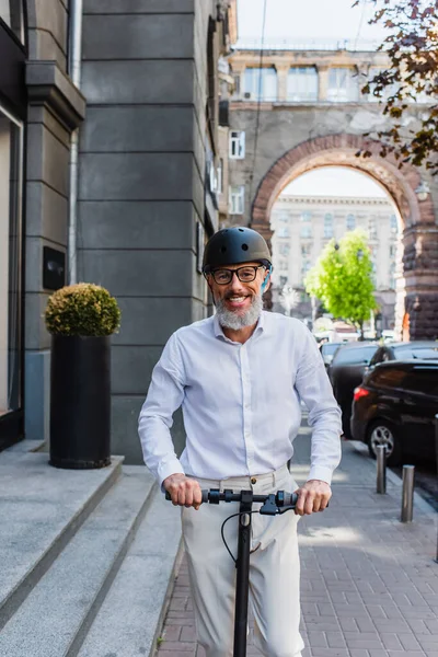 Smiling and mature man in shirt and helmet riding electric scooter — Photo de stock