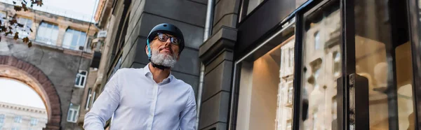 Low angle view of mature man in shirt and helmet outside, banner — Photo de stock