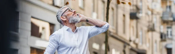 Happy middle aged man in glasses talking on smartphone and looking up, banner — Stock Photo