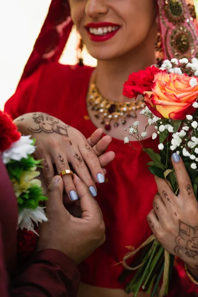 Partial view of happy indian man wearing wedding ring on finger of bride — Stock Photo