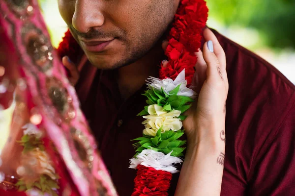 Vue recadrée de la mariée indienne portant une guirlande florale sur le marié — Photo de stock