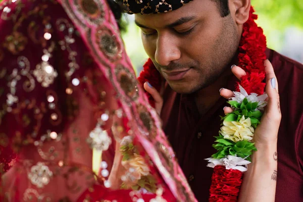 Indian bride wearing floral garland on bridegroom outside — Stock Photo