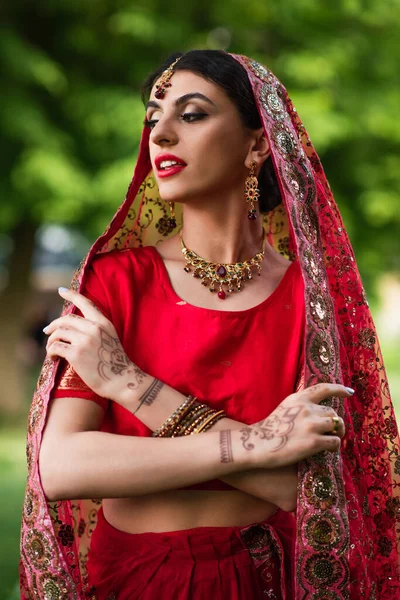 Young indian bride in red sari and headscarf with ornament — Stock Photo