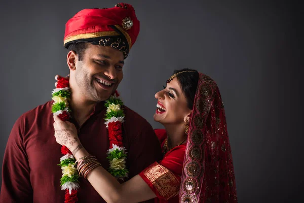 Noiva indiana alegre vestindo guirlanda no noivo isolado em cinza — Fotografia de Stock