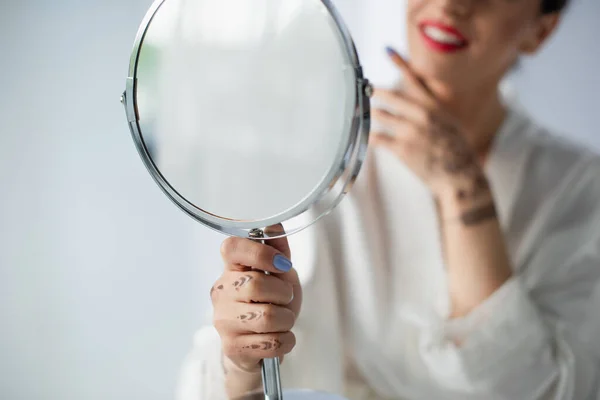 Vista cortada de noiva indiana turva e feliz olhando espelho isolado no branco — Fotografia de Stock