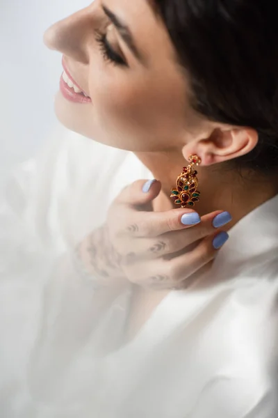 High angle view of happy indian bride wearing earring while getting ready for wedding isolated on white — Stock Photo