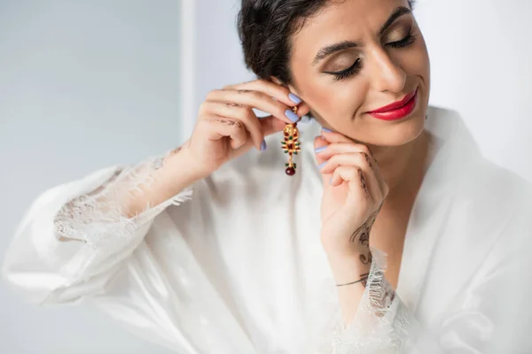 Smiling indian bride wearing earring on white — Stock Photo