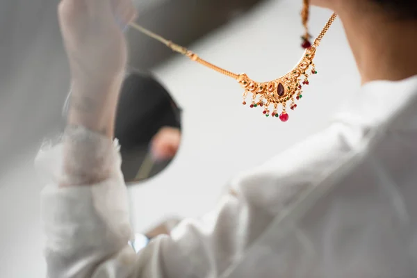 Cropped view of young bride holding necklace on white — Stock Photo