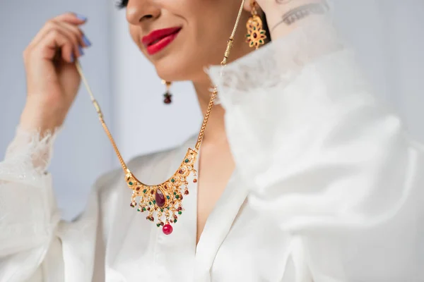 Vue recadrée de jeune mariée indienne tenant collier sur blanc — Photo de stock