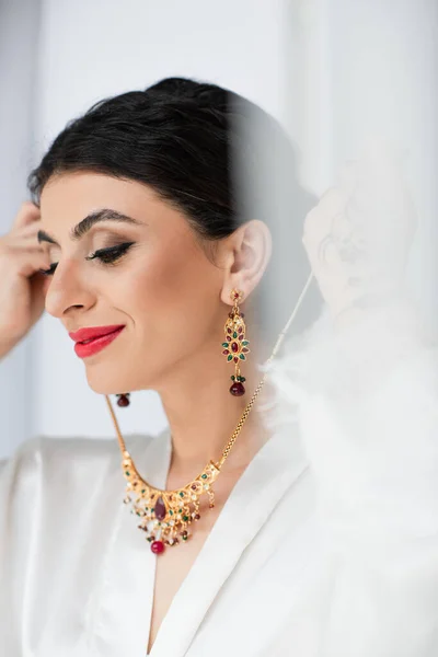 Happy young indian bride wearing necklace on white — Stock Photo