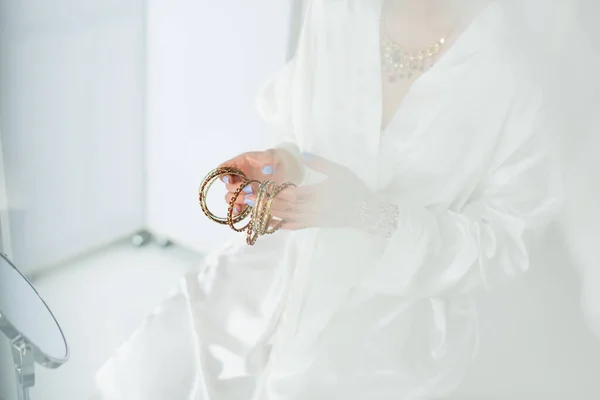 Vista recortada de la novia india joven sosteniendo pulseras cerca del espejo - foto de stock