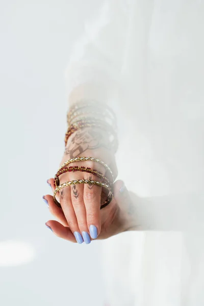 Vista ritagliata di giovane sposa indiana con mehndi indossa bracciali su bianco — Foto stock