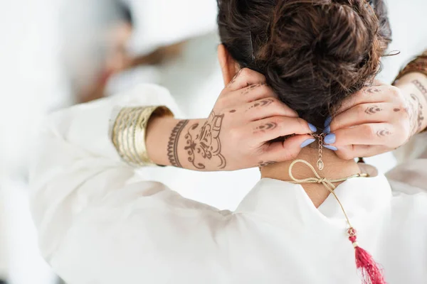 Vue arrière de la mariée indienne avec mehndi sur les mains portant un collier — Photo de stock