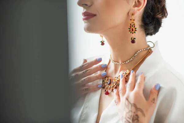 Vue recadrée de mariée indienne touchant collier sur blanc — Photo de stock