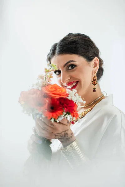 Heureuse mariée indienne avec mehndi tenant bouquet de fleurs sur blanc — Photo de stock