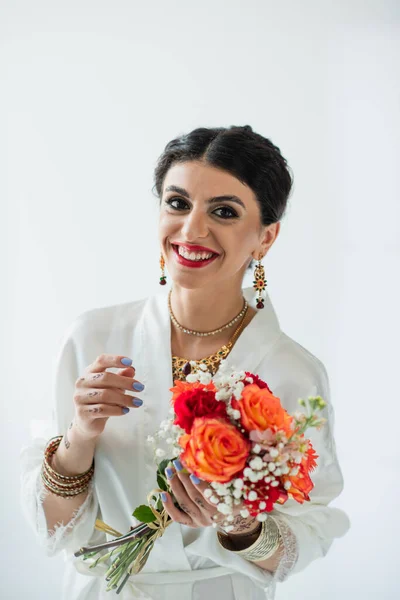 Sposa indiana gioiosa con mehndi che tiene mazzo di fiori su bianco — Foto stock