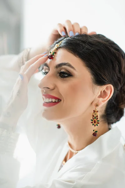 Noiva indiana sorrindo e vestindo jóias na cabeça — Fotografia de Stock