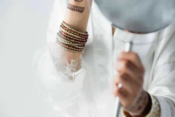 Cropped view of indian bride with mehndi holding mirror on white — Stock Photo