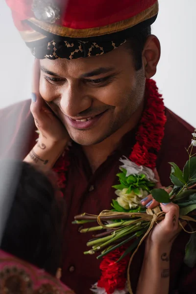 Невіста індіанця, яка торкається щасливого молодого в тюрбані ізольованого на білому — стокове фото
