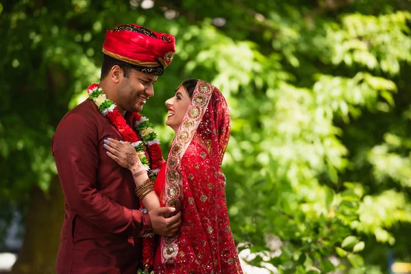 Feliz indio hombre en turbante abrazando alegre novia con mehndi en sari y pañuelo en la cabeza - foto de stock
