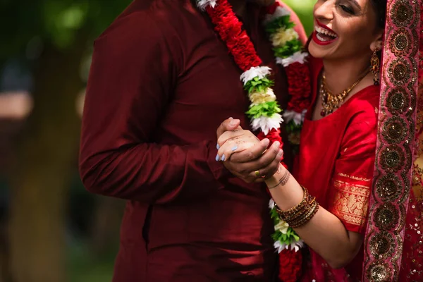 Обрізаний вид на індійського чоловіка, що тримає руки з веселою нареченою в сарі — стокове фото