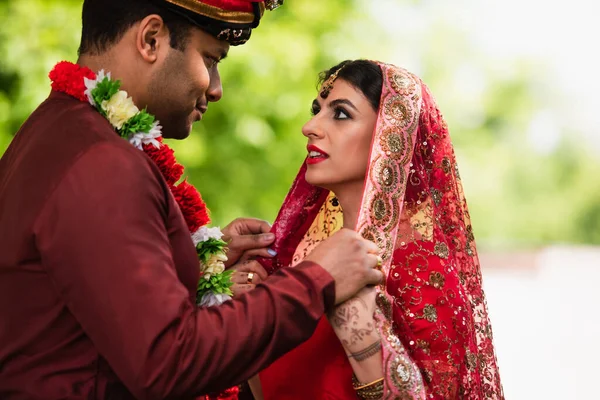 Indian man adjusting headscarf on bride in sari — Stock Photo