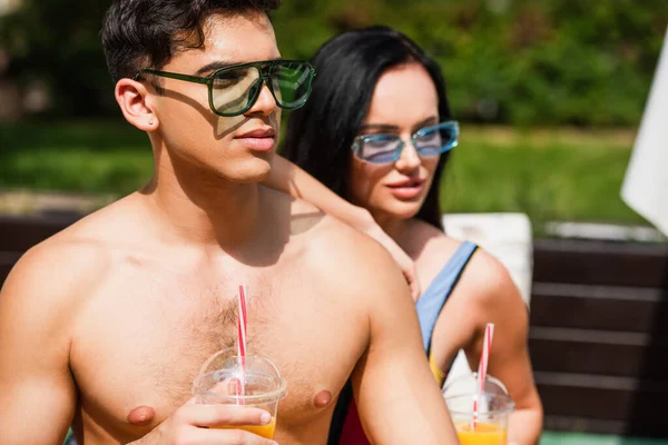 Shirtless homem segurando suco de laranja perto de namorada turva — Fotografia de Stock