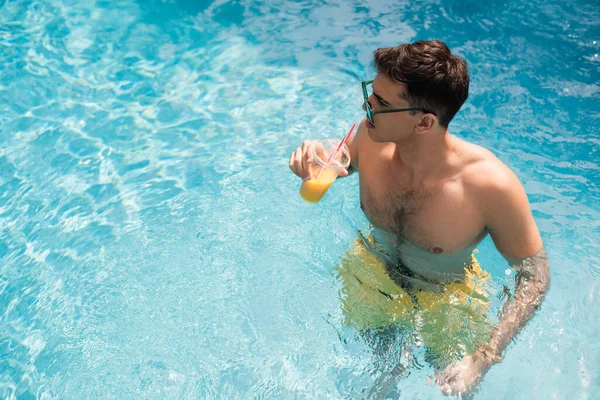 High angle view of man holding takeaway drink in swimming pool — Stock Photo