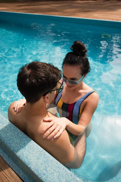 Pretty woman hugging young boyfriend in swimming pool — Stock Photo