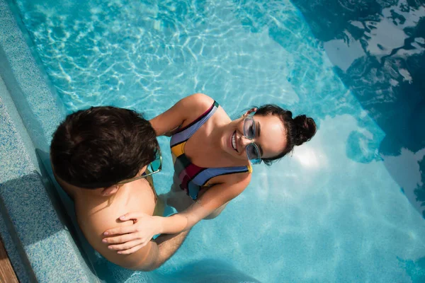 Blick aus der Vogelperspektive auf eine fröhliche Frau, die sich mit ihrem Freund im Swimmingpool entspannt — Stockfoto