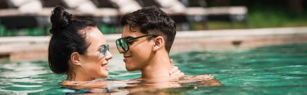 Seitenansicht einer lächelnden Frau, die im Schwimmbad den Hals ihres Freundes berührt, Banner — Stockfoto