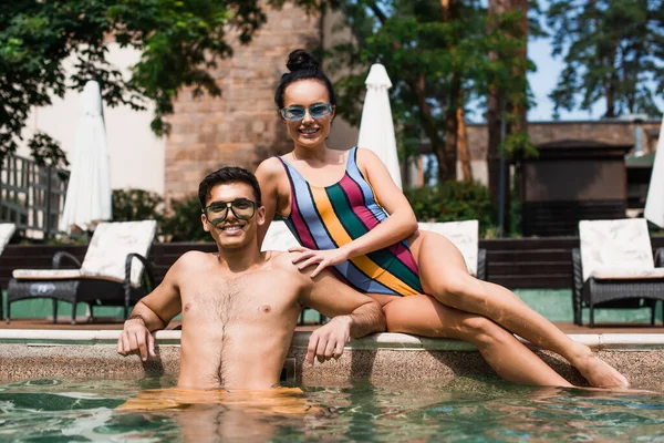 Sorridente coppia guardando la fotocamera in piscina sul resort — Foto stock