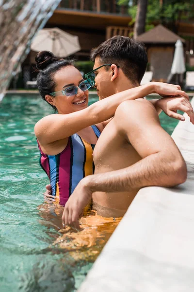 Красива жінка обіймає хлопця біля розмитого басейну — стокове фото