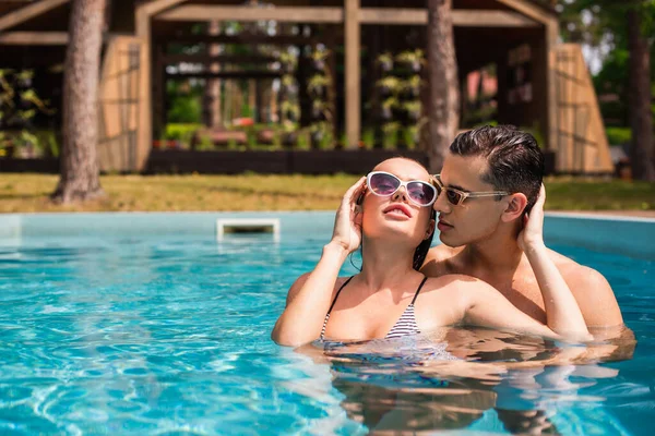 Сексуальная женщина с закрытыми глазами, стоящая рядом с парнем в бассейне — стоковое фото