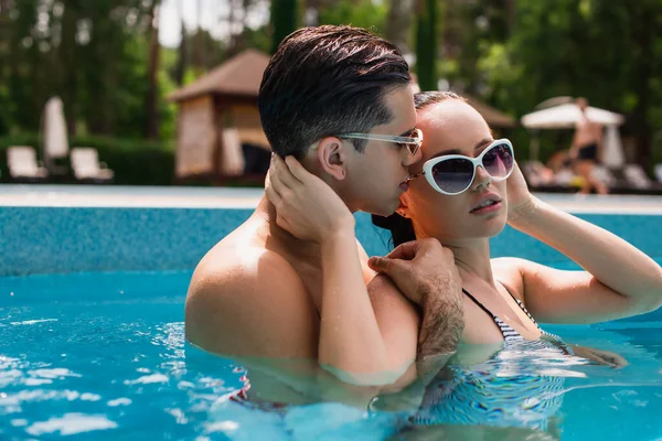 Sexy couple touching each other in swimming pool during weekend — Stock Photo