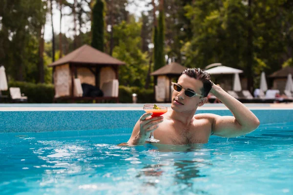 Mann mit Cocktail rastet in Schwimmbad auf Ferienanlage aus — Stockfoto