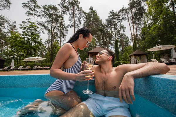 Jeune couple avec du vin se regardant dans la piscine — Photo de stock